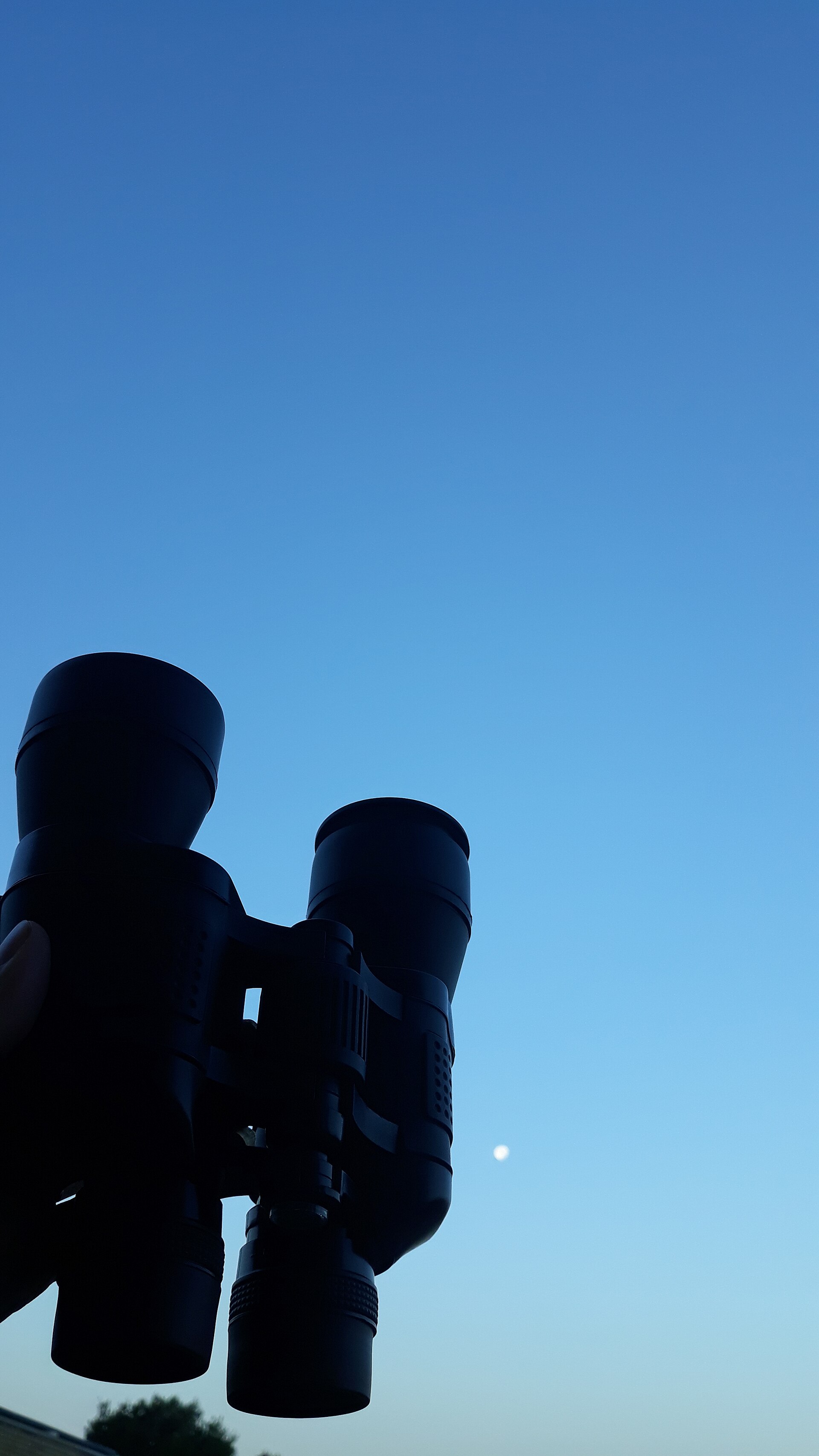 Binoculars pointed toward the Moon in twilight