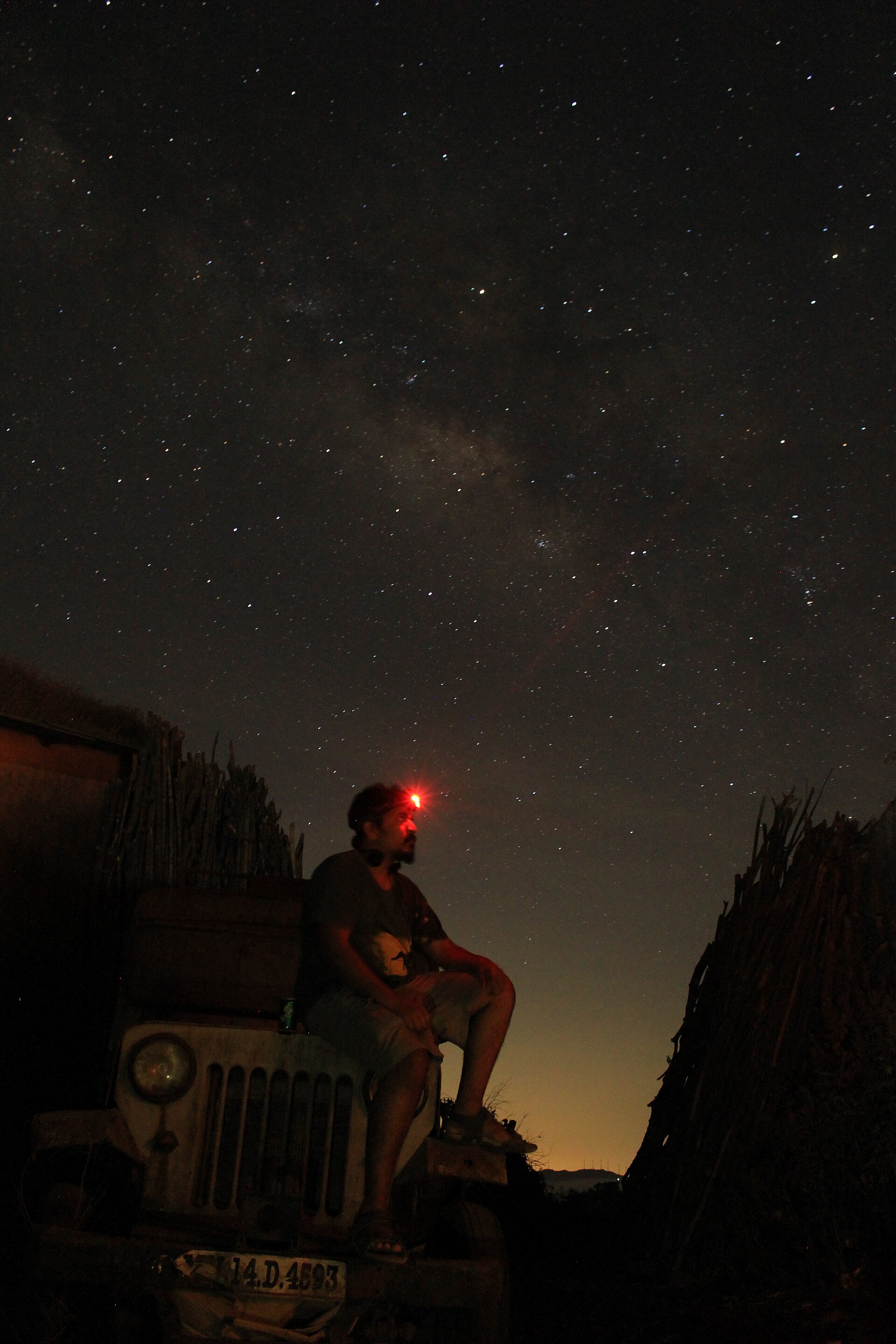 A stargazer under the Milky Way in India with a red headlamp